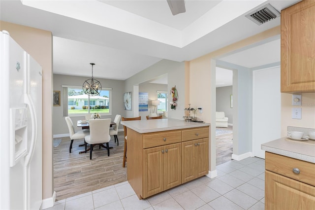 kitchen featuring light tile patterned floors, kitchen peninsula, pendant lighting, a chandelier, and white refrigerator with ice dispenser