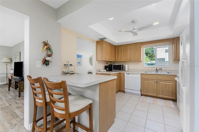 kitchen with a kitchen breakfast bar, dishwasher, kitchen peninsula, and a raised ceiling