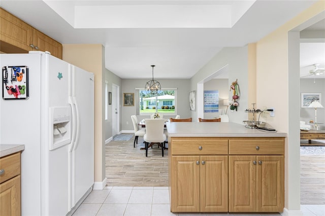 kitchen featuring kitchen peninsula, ceiling fan, light tile patterned flooring, hanging light fixtures, and white refrigerator with ice dispenser