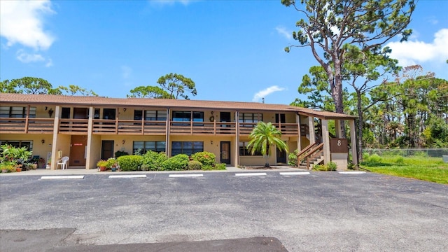 view of building exterior featuring uncovered parking and fence