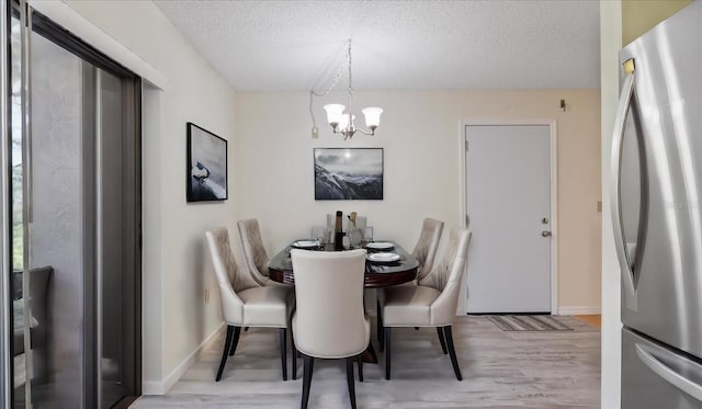 dining room featuring an inviting chandelier, light wood-style flooring, baseboards, and a textured ceiling