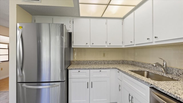 kitchen featuring a sink, stainless steel appliances, white cabinets, and decorative backsplash