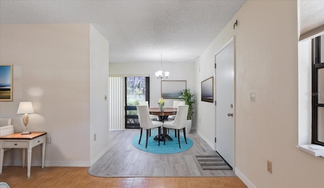 dining area featuring a notable chandelier, wood finished floors, baseboards, and a textured ceiling