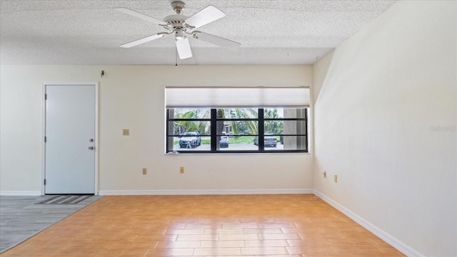 spare room featuring light wood finished floors and a textured ceiling