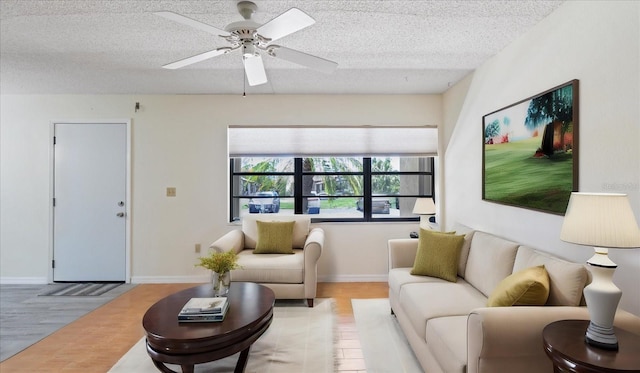 living area featuring baseboards, a textured ceiling, and light wood finished floors