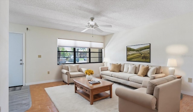 living area featuring light wood finished floors, baseboards, a textured ceiling, and ceiling fan