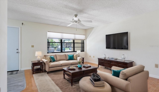 living room featuring light wood finished floors, baseboards, a textured ceiling, and ceiling fan