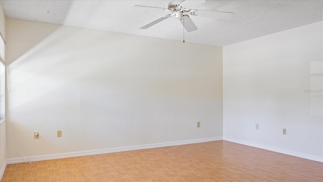 spare room featuring baseboards, a textured ceiling, light wood-type flooring, and a ceiling fan