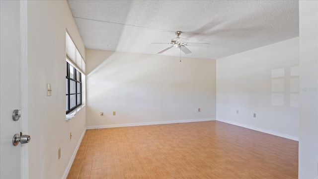 spare room with baseboards, a textured ceiling, wood finished floors, and a ceiling fan