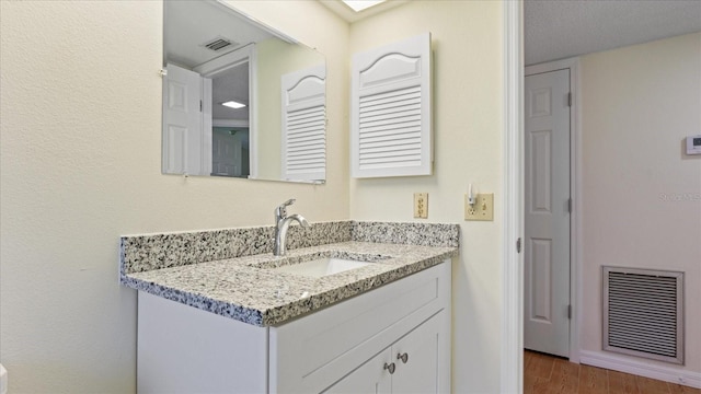 bathroom with visible vents, wood finished floors, and vanity