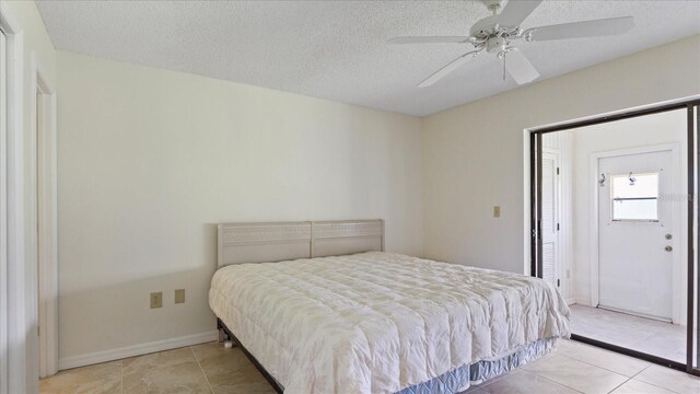 bedroom featuring tile patterned floors, baseboards, a textured ceiling, and a ceiling fan