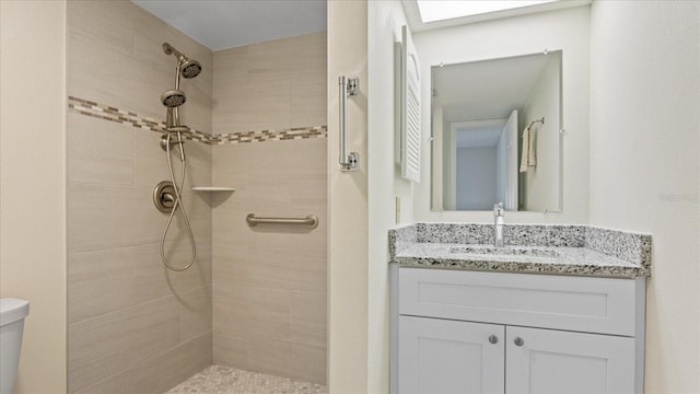 bathroom with tiled shower, toilet, and vanity