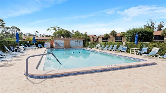 community pool with a patio area and fence