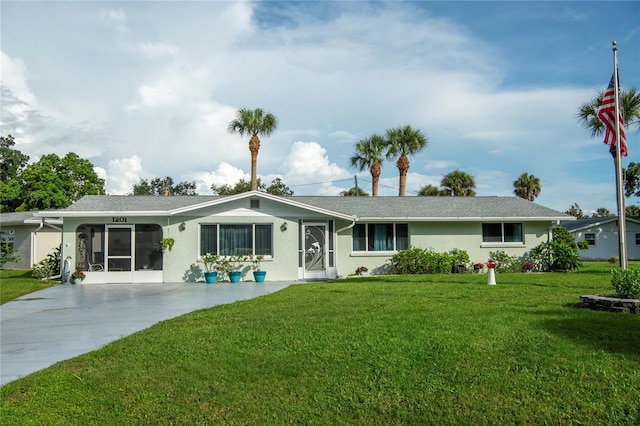 rear view of property with driveway, stucco siding, and a yard