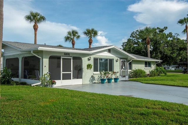 back of property with a sunroom, a yard, and stucco siding