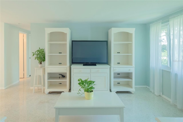 living area featuring light speckled floor, baseboards, and built in features