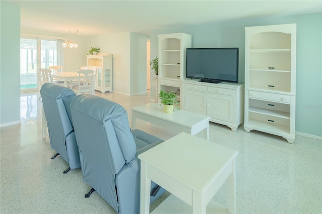 living room with baseboards, a chandelier, and light speckled floor