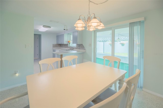 dining space featuring light speckled floor, baseboards, and an inviting chandelier