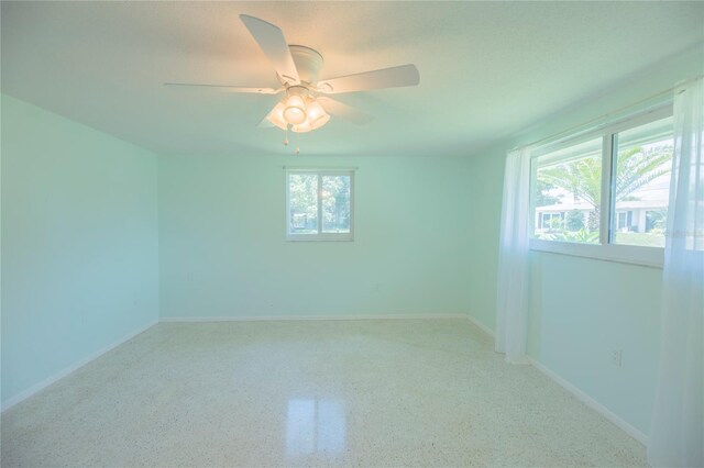 spare room featuring ceiling fan, baseboards, and speckled floor