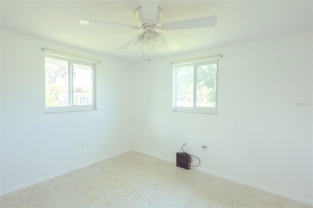 spare room with a ceiling fan, a healthy amount of sunlight, and baseboards