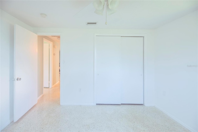 unfurnished bedroom featuring light speckled floor, a closet, visible vents, and a ceiling fan