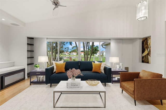 living room with light hardwood / wood-style floors, high vaulted ceiling, and ceiling fan