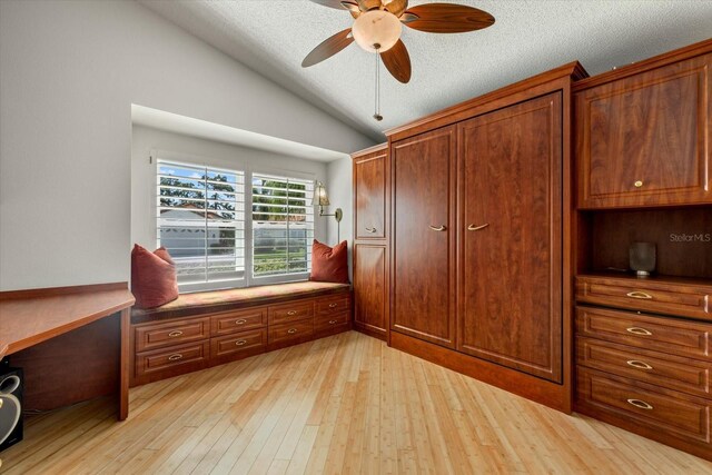 bedroom featuring light wood-type flooring, vaulted ceiling, ceiling fan, and a textured ceiling