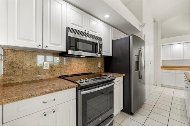 kitchen with backsplash, stone counters, light tile patterned floors, stainless steel appliances, and white cabinets