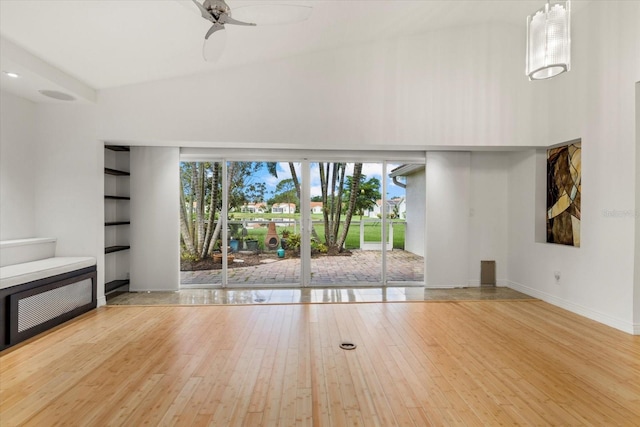 unfurnished living room with light hardwood / wood-style flooring, ceiling fan, and high vaulted ceiling