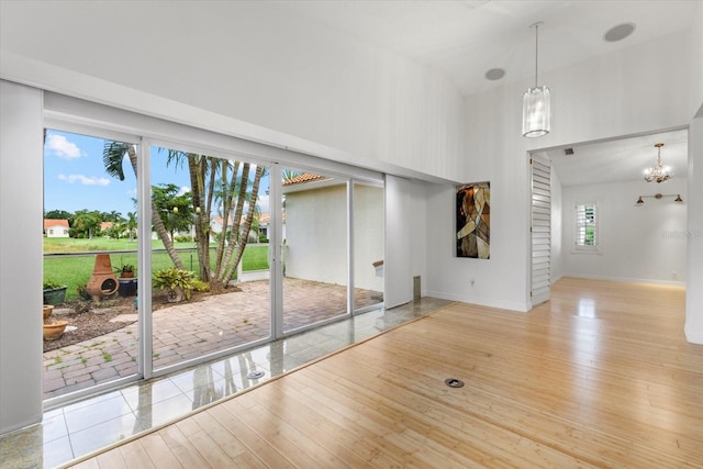 interior space with high vaulted ceiling, light wood-type flooring, and an inviting chandelier