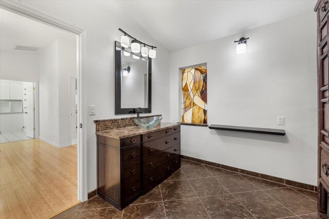 bathroom featuring lofted ceiling, vanity, and wood-type flooring