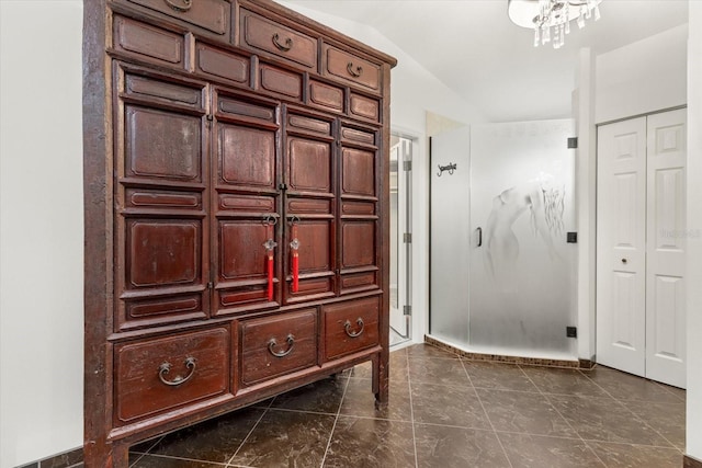 interior space with dark tile patterned flooring, a notable chandelier, and lofted ceiling