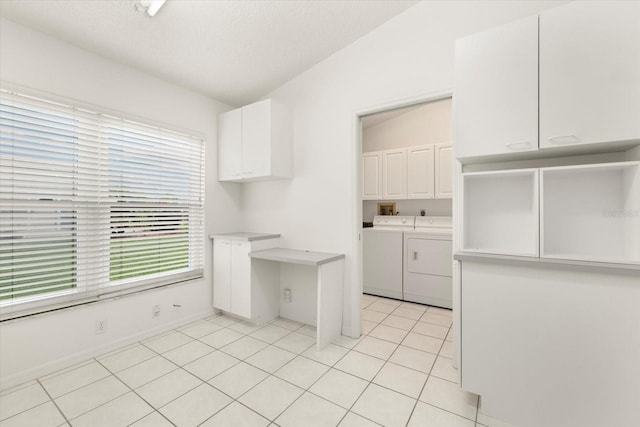 kitchen with a wealth of natural light, white cabinetry, lofted ceiling, and washer and clothes dryer