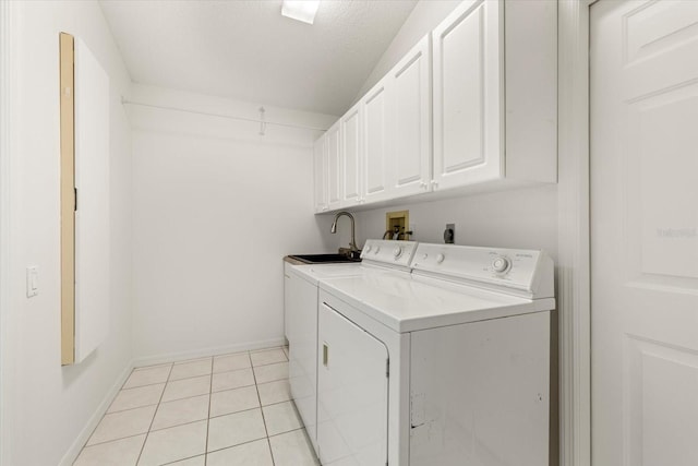 laundry area featuring sink, washing machine and dryer, cabinets, and light tile patterned floors