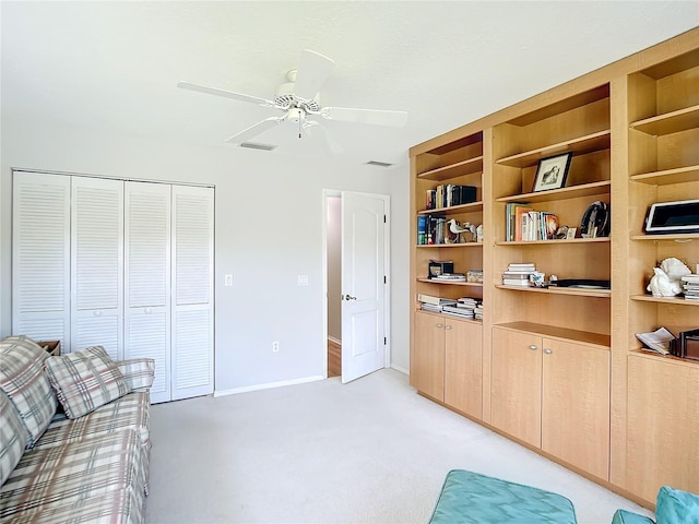 interior space with built in features, light colored carpet, and ceiling fan