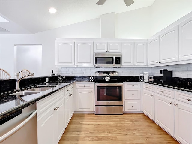 kitchen featuring white cabinetry, stainless steel appliances, light hardwood / wood-style flooring, and dark stone countertops