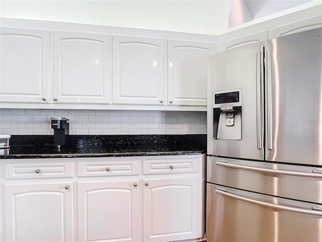 kitchen with white cabinetry, stainless steel fridge, and dark stone counters