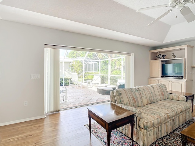 living room featuring ceiling fan, lofted ceiling, and light hardwood / wood-style floors