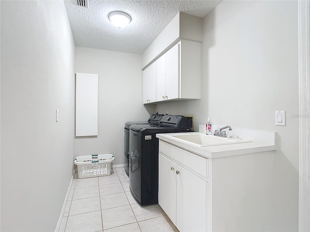 washroom with sink, washing machine and dryer, cabinets, a textured ceiling, and light tile patterned flooring