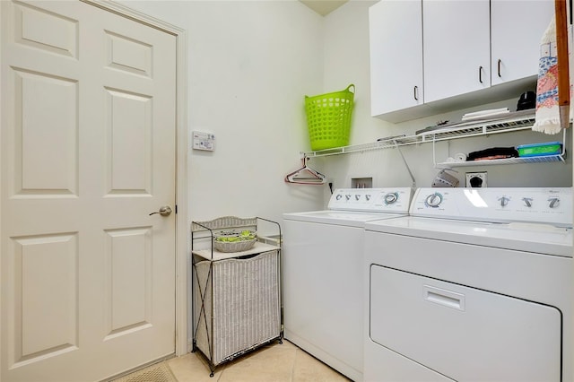 clothes washing area with cabinet space, independent washer and dryer, and light tile patterned floors