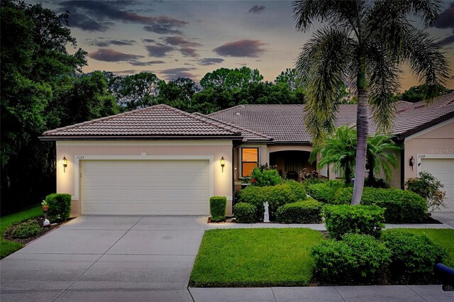 view of front of house featuring a garage, driveway, a tiled roof, and stucco siding