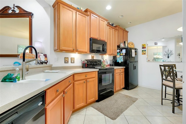 kitchen featuring light countertops, a sink, black appliances, and light tile patterned floors