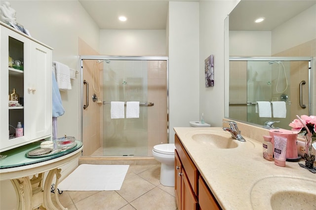 full bath with double vanity, toilet, a sink, a shower stall, and tile patterned floors