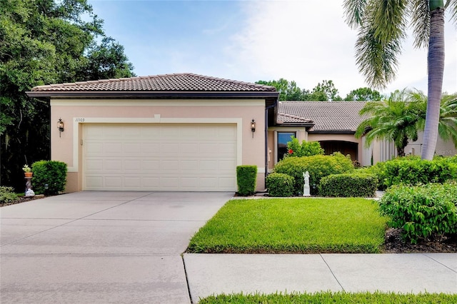 view of front of house with an attached garage, concrete driveway, a tiled roof, stucco siding, and a front lawn