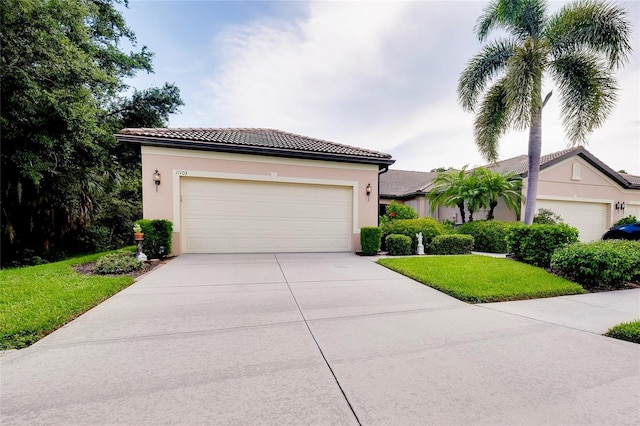 view of front of home featuring driveway, a tiled roof, a front lawn, and stucco siding