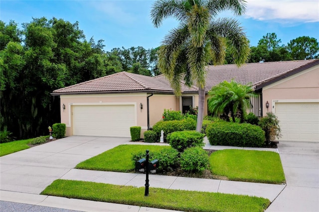 view of front of property featuring driveway, an attached garage, a tile roof, and stucco siding