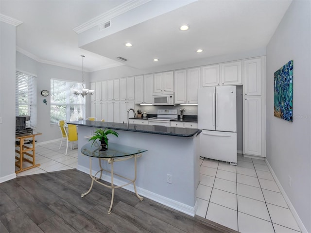 kitchen with pendant lighting, white cabinetry, ornamental molding, a kitchen island with sink, and white appliances