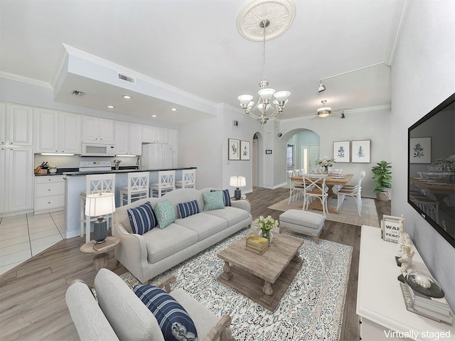 living room featuring crown molding and ceiling fan with notable chandelier