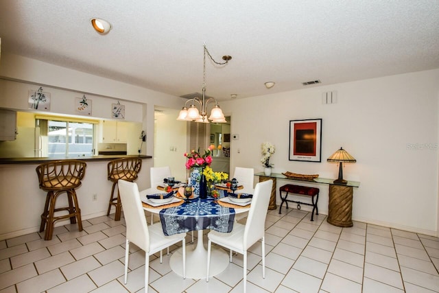 tiled dining space with a notable chandelier and a textured ceiling