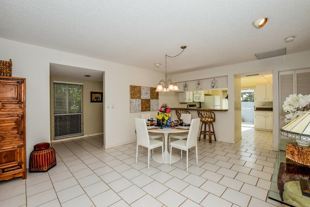 dining space featuring an inviting chandelier, a textured ceiling, and light tile patterned floors